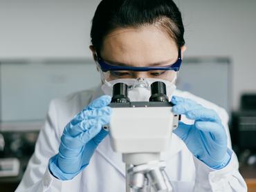 Egy orvos-kutató a laboratóriumban vizsgál egy vírust vagy baktériumot a mikroszkópba nézve