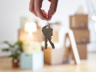 Közelkép egy nőről, aki az új otthonában a ház kulcsát tartja a kezében