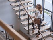 Üzleti élet, egy nő, aki egy professzionális vállalatnál lépcsőn halad felfelé, hogy eljusson az irodájába. Lépcsőház, vezetői szerep és egy üzletasszony, aki a munkahelye épületében lépcsőn halad felfelé, miközben siet