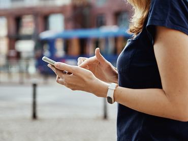 Egy nő okostelefont használ a város utcáján.