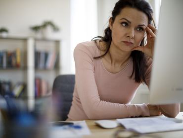 Aggódó nő a számítógép képernyőjét nézi
