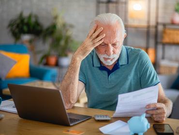 nyugdíjas férfi asztalnál ül gondolkodik olvas