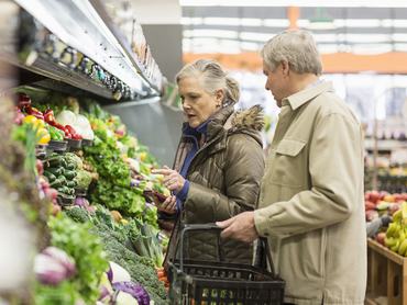 Egy nyugdíjas pár válogat a zöldségek és gyümölcsök között a boltban vagy piacon