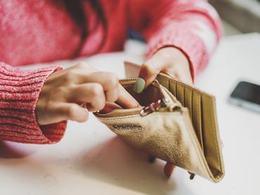 Egy nő aprópénzt keres a pénztárcájában