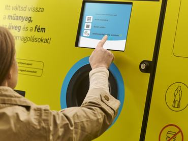Egy nő megérinti a REpont üvegvisszaváltó automata kijelzőjét