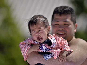 szumóbirkózó síró kislánnyal a kezében