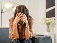 Stresszes fiatal nő az arcát a kezébe temetve sír