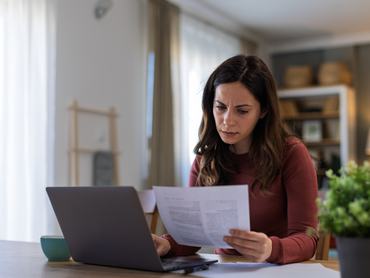 Egy fiatal nő a kanapén ülve laptopot és hitelkártyát használ online vásárláshoz és rendeléshez