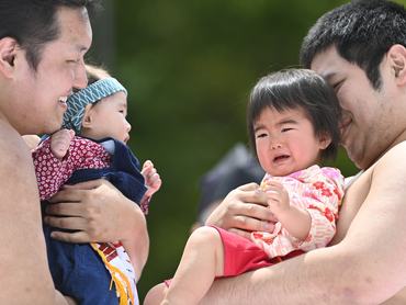 2 szumóbirkózó kisgyerekkel a kezében