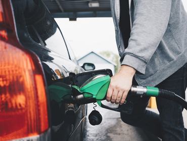 Egy fiatal férfi benzint tankol az autójába a benzinkúton.