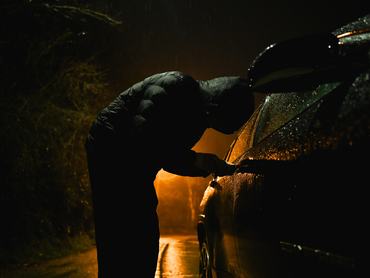 Man with hood trying to break into car.