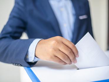 Közelkép egy emberi kézről, amint szavaz, választ és döntést hoz a szavazófülkében. Szavazás, szavazóurna, választás, népszavazás