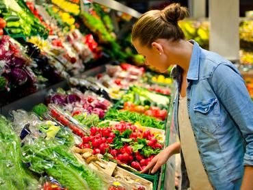 Egy fiatal szőke nő a szupermarketben gyümölcsöt keres